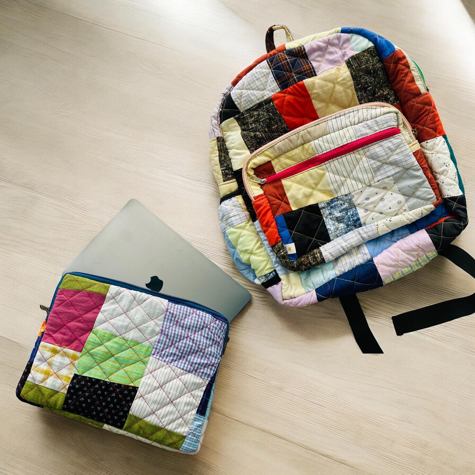 Quilted patchwork backpack and matching laptop sleeve on a wooden floor, with a MacBook partially inserted. The set is made from colorful fabric scraps, designed to carry everyday tech essentials stylishly. Perfect for school, office, or travel use. Eco-friendly, upcycled, and handmade – this set makes a thoughtful gift for students, digital nomads, or minimalist travelers seeking functionality and flair.