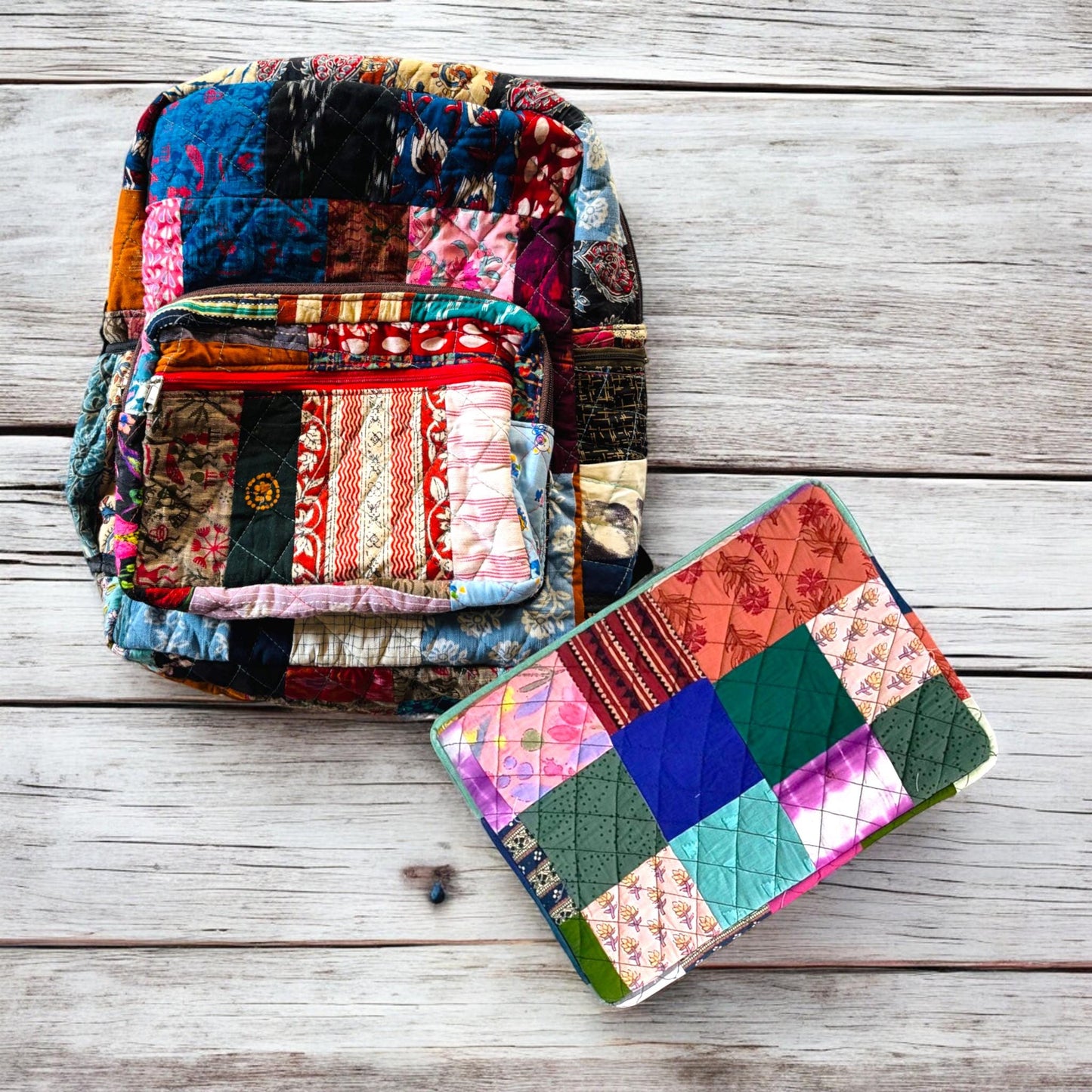 Backpack and padded laptop sleeve placed on a wooden floor. The MacBook is partially inserted into the sleeve, highlighting its snug fit and functional use. Both accessories feature eco-friendly, handmade patchwork crafted from upcycled cotton fabric. Ideal for gifting, school, or remote work. A sustainable, zero-waste solution for creative users who love bold, colorful designs. This showcases the Indian print combinations of backpack and laptop sleeve