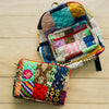 Colorful handmade backpack and laptop sleeve with vivid patchwork featuring florals, tribal prints, and geometric patterns. Shown on a light wooden floor, this set is crafted using rescued textile scraps, promoting a zero-waste lifestyle. Ideal for eco-conscious students, creatives, or professionals who need functional yet expressive accessories for school, travel, or daily errands.